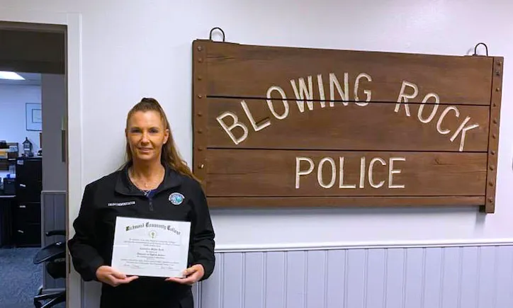 911 Communications & Operations graduate Casandra Reid holds her degree by sign for Blowing Rock Police Department.
